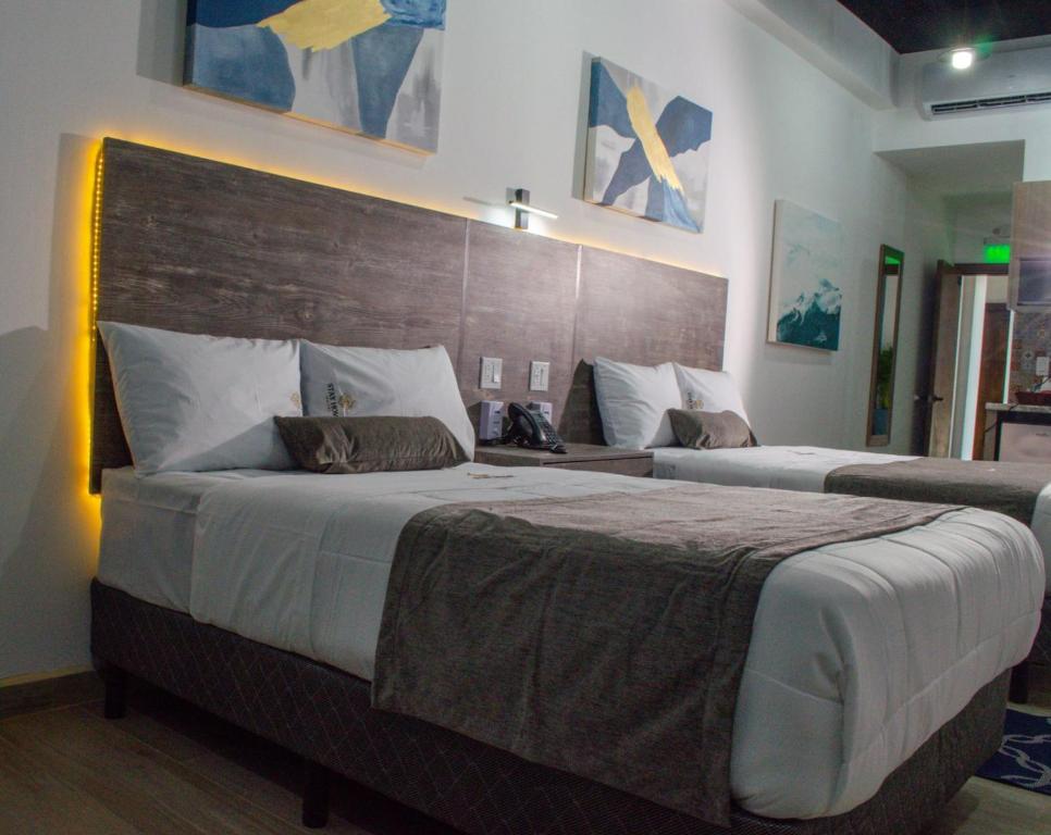 a bedroom with two beds and a wooden headboard at Hotel StayHome in Ensenada