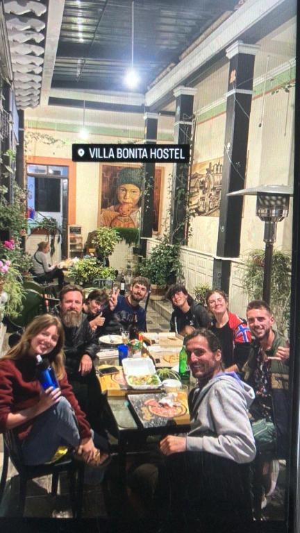 een groep mensen die rond een tafel zitten bij Villa Bonita Hostel in Riobamba