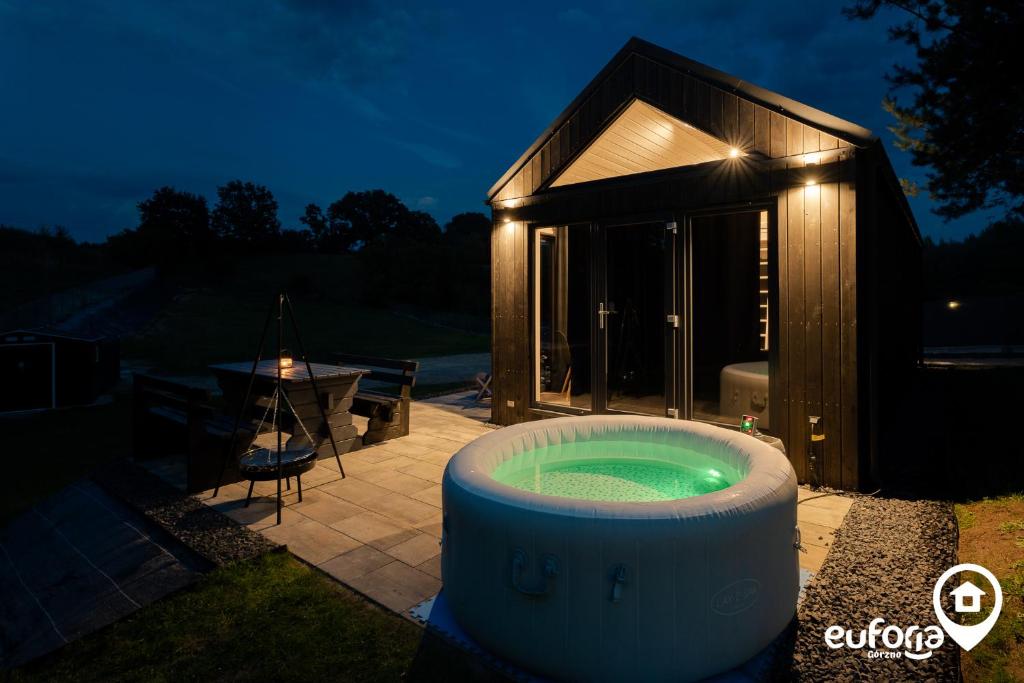 a hot tub in front of a small building at Euforia Górzno - nowoczesne, klimatyzowane domki z jacuzzi i sauną in Górzno