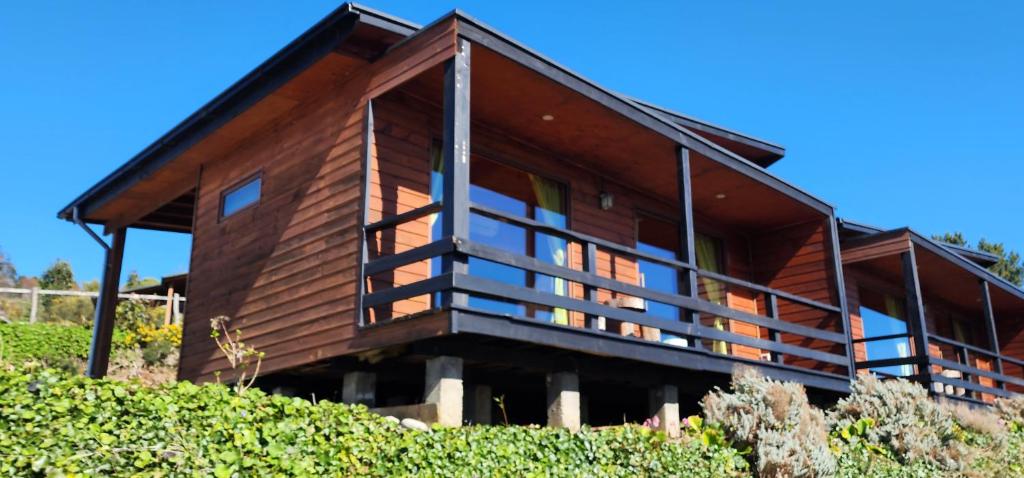 a wooden house with a balcony on a hill at Hotel y Cabañas Terrazas Vista al Mar hct in Ancud