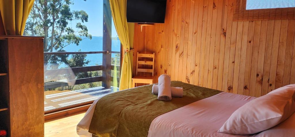 a bedroom with a bed and a large window at Hotel y Cabañas Terrazas Vista al Mar hct in Ancud