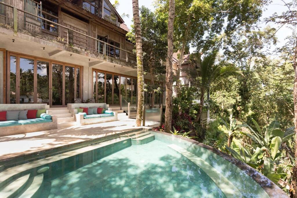 a swimming pool in front of a house at RiverView Gardens in Ubud