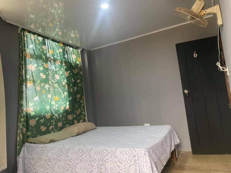 een slaapkamer met een bed en een groen gordijn bij Hotel Rio Puntarenas in Puntarenas