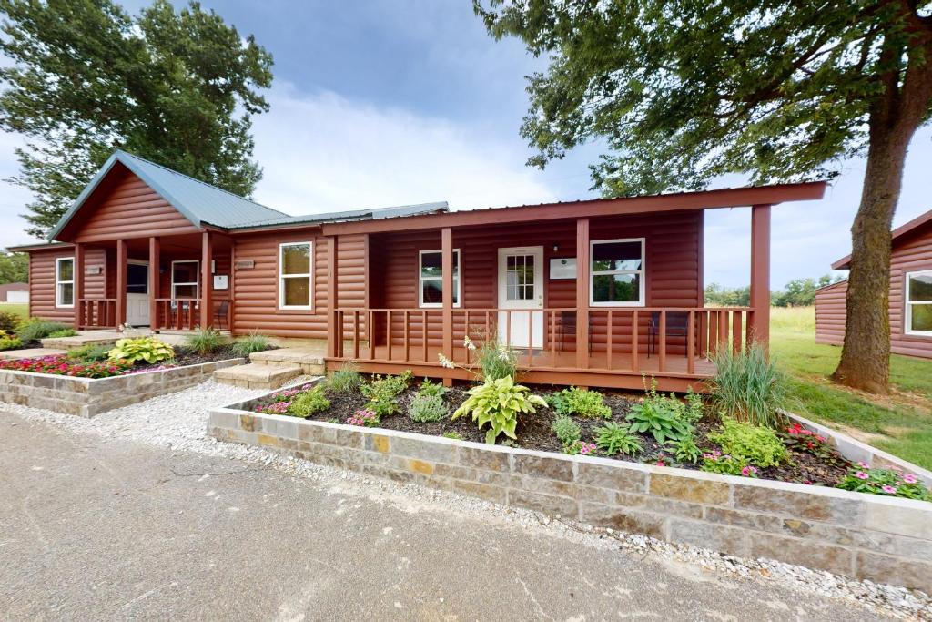 ein Blockhaus mit einer Veranda und Gartenanlagen in der Unterkunft Cabin 1 & 2 in Bentonville