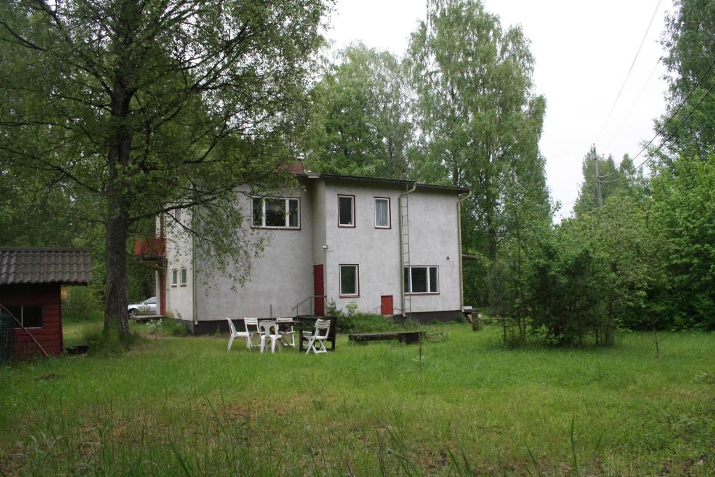a house with two chairs and a table in a field at Villa Vanha Valko in Lovisa