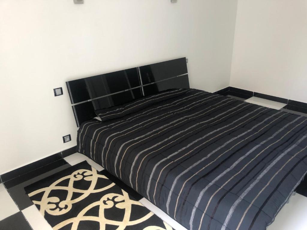 マルセイユにあるChambre 2 places avec salle de bainのベッドルーム1室(ベッド1台、黒いヘッドボード、ラグ付)