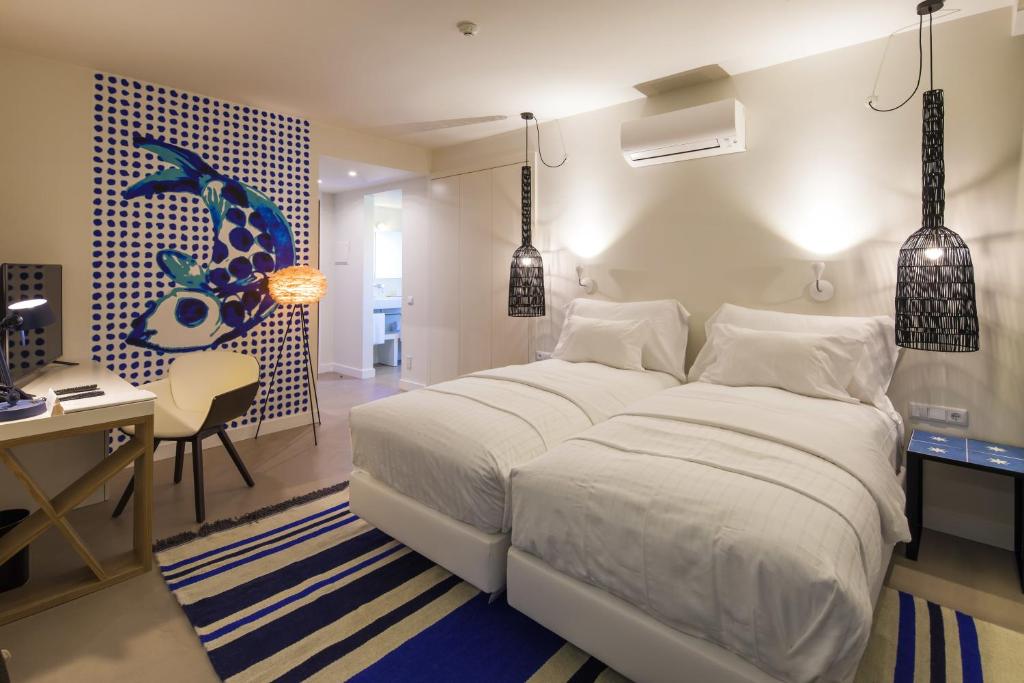 a bedroom with a large white bed and a desk and a desk at Costa d'Oiro Ambiance Village in Lagos