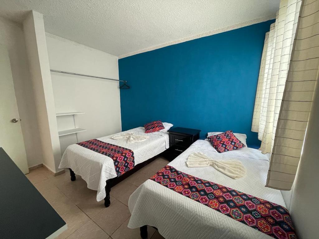 Cette chambre comprend 2 lits et un mur bleu. dans l'établissement Departamento en Pomoca, à Palenque