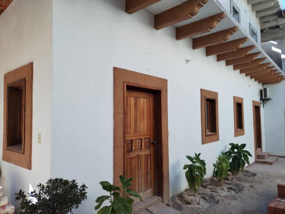 - un bâtiment blanc avec une porte en bois dans l'établissement Carmen Graciela, à Álamos
