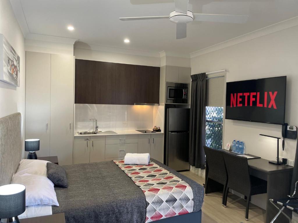 a bedroom with a bed and a desk and a kitchen at Northpoint Motel Apartments in Toowoomba