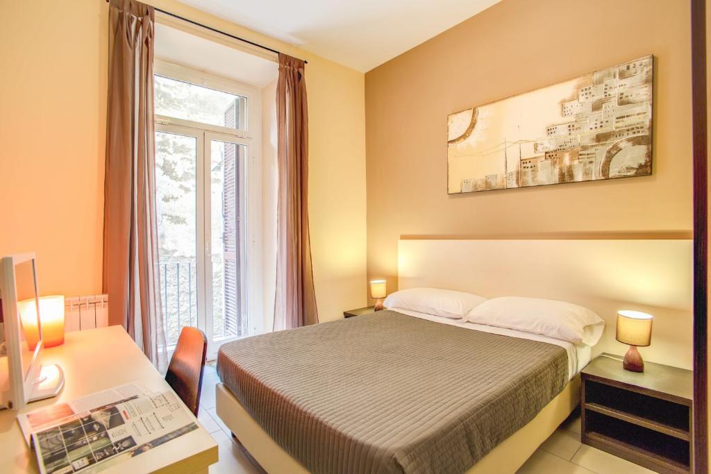 a bedroom with a bed and a desk and a window at Hotel Mosaic Central Rome in Rome