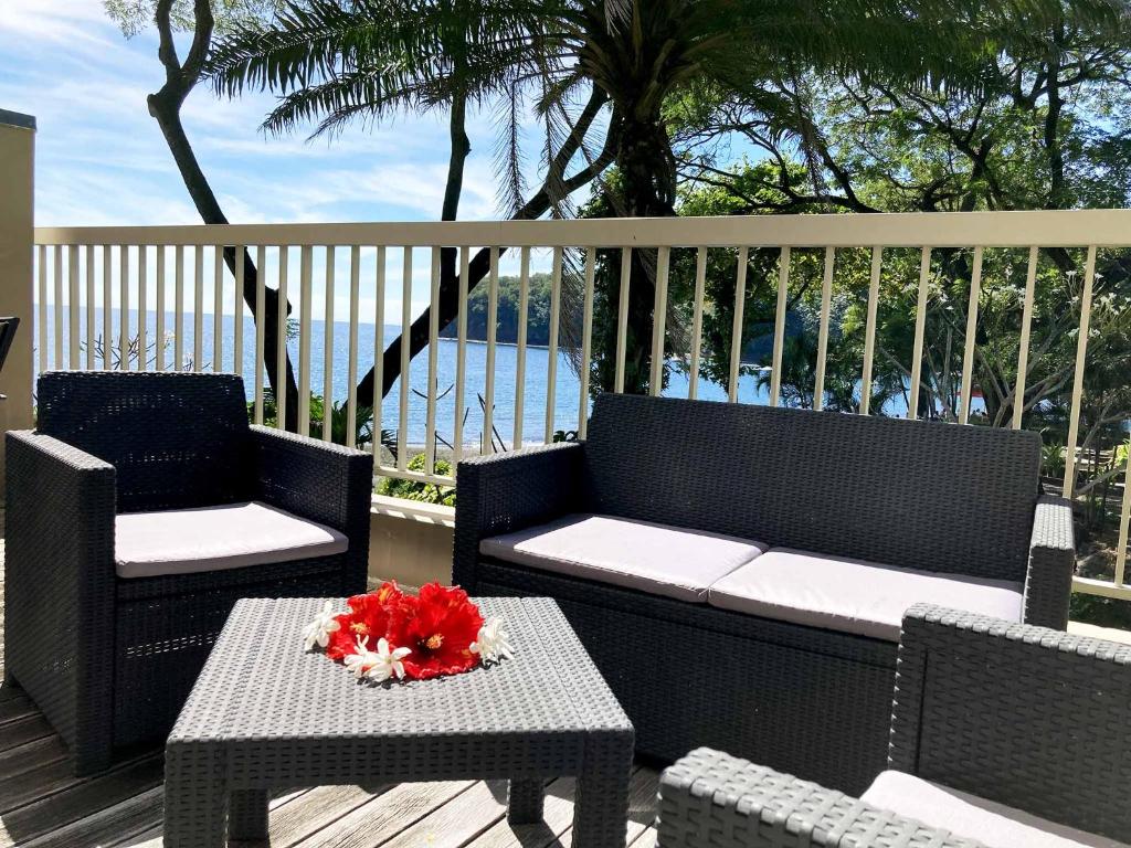 a patio with two chairs and a table with a flower on it at Tahiti Lafayette Beach Lodge in Arue
