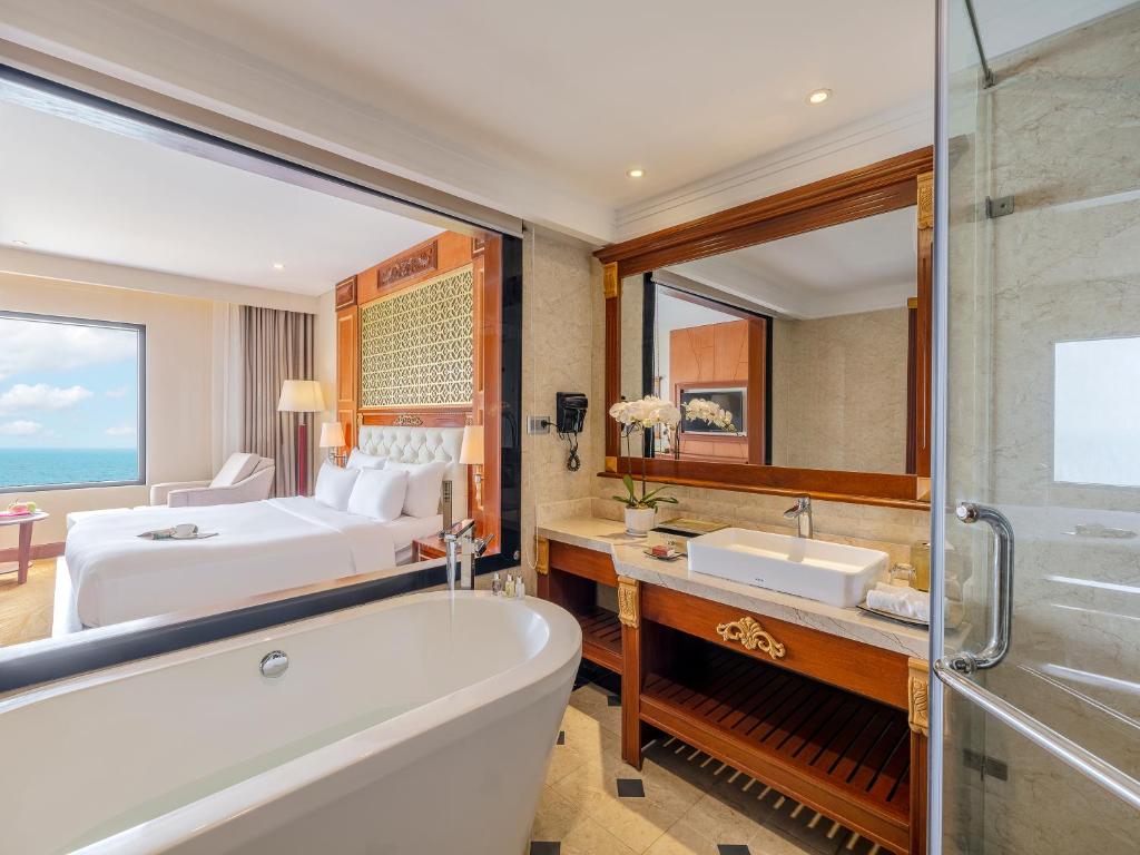 a bathroom with a tub and a bedroom at DLG Hotel Danang in Da Nang