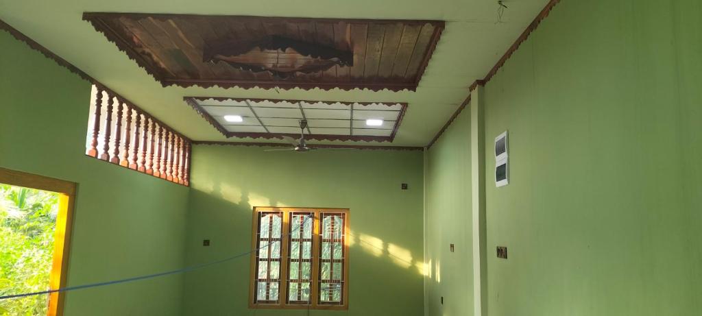 Habitación con paredes verdes y techo. en MR JEY Deluxe, en Jaffna