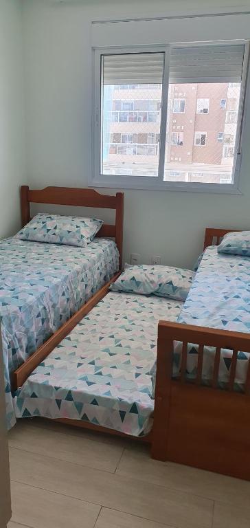 2 camas individuais num quarto com 2 janelas em Resort Itanhaém - Pé na areia em Itanhaém