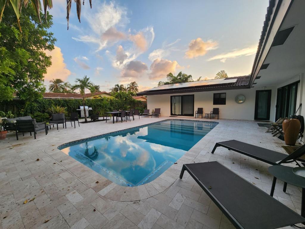 a swimming pool in a yard with tables and chairs at Lighthouse Guest Suites in Fort Lauderdale
