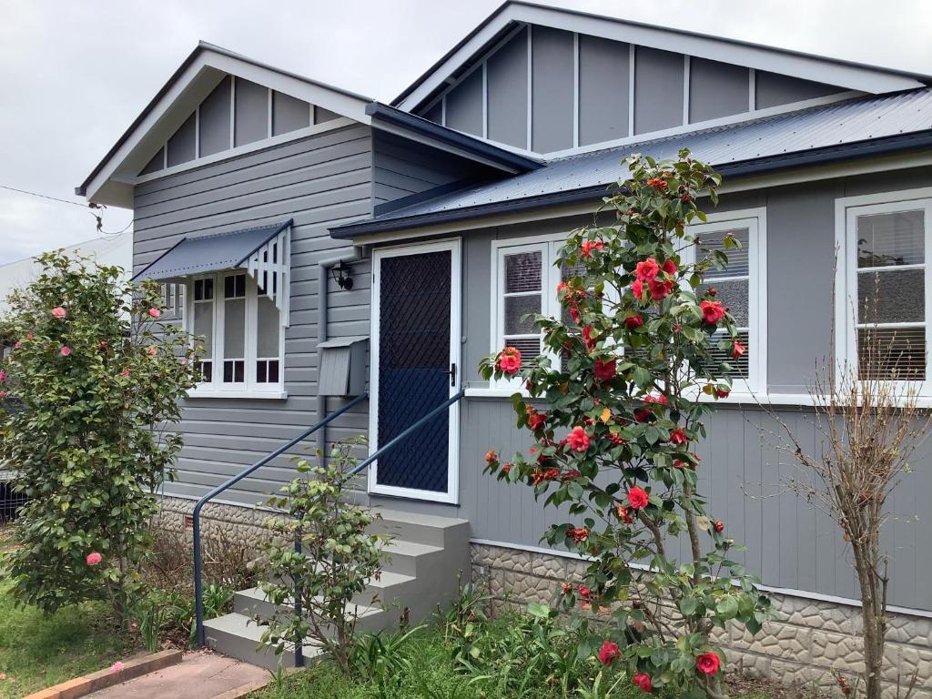 a gray house with red roses in front of it at Rosellas on Corundum Cottage - treat yourself! in Stanthorpe