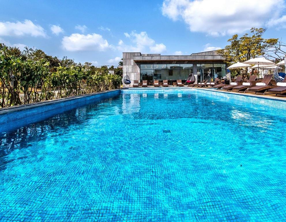 uma grande piscina com água azul em frente a um edifício em Jeju Breeze em Seogwipo