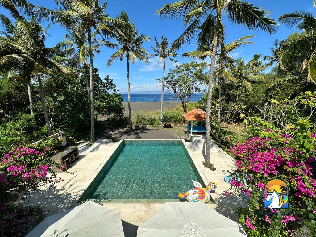 a swimming pool with a view of the ocean and palm trees at Villa Black Pearl - by Unicorn Villas Bali in Padangbai