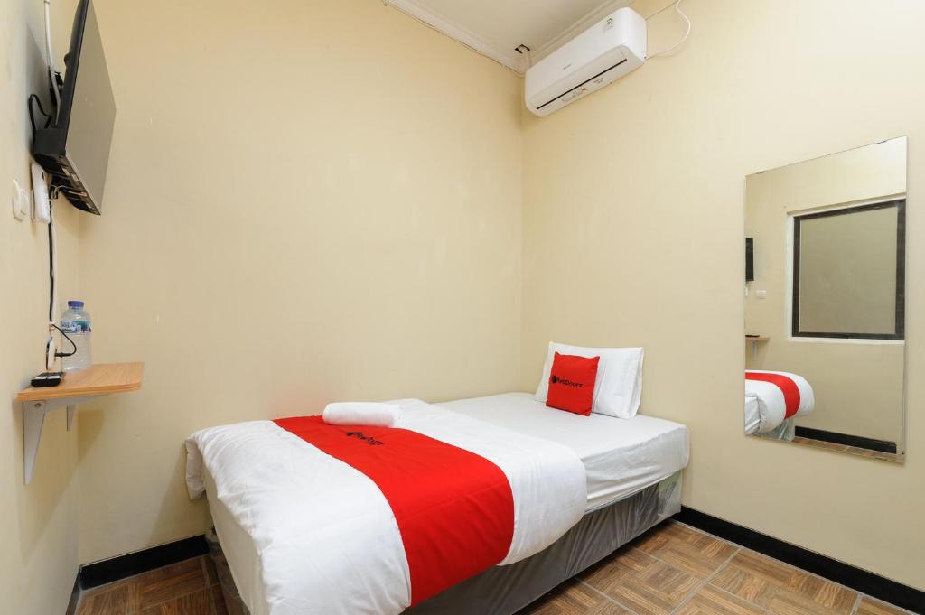 ein Schlafzimmer mit einem Bett mit einer rot-weißen Decke in der Unterkunft RedDoorz near The Jungle Waterpark Bogor in Bogor