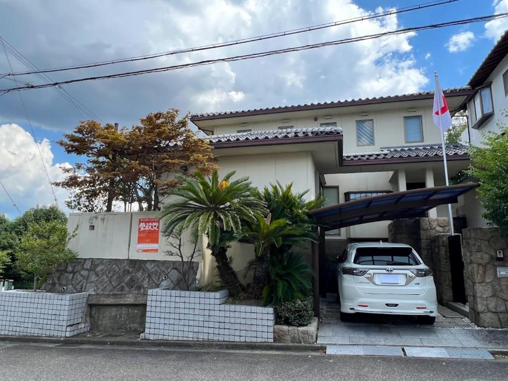 un coche blanco estacionado frente a una casa en Ken House Osaka en Takatuki