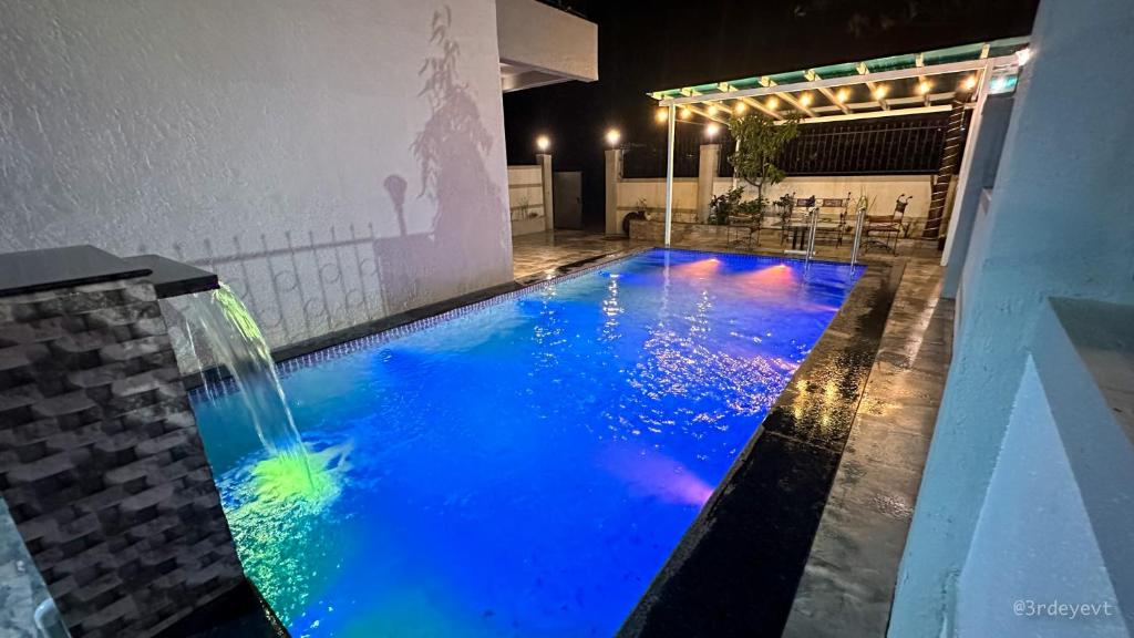 a swimming pool with a waterfall and blue water at Mystic Dreamville 3BHK Villa Lonavala in Lonavala