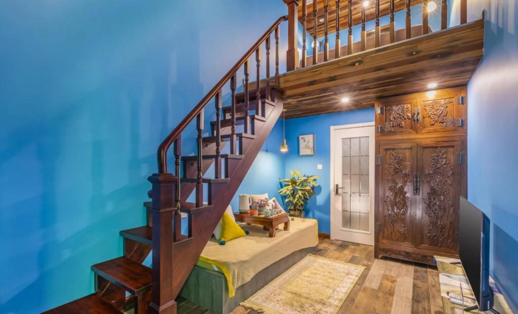 a living room with blue walls and a spiral staircase at Beijing Shixi Inn - Wangfujing Nanluoguxiang Branch in Beijing
