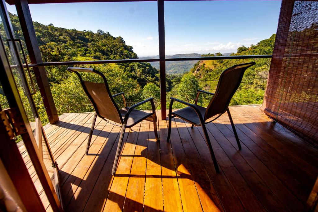 two chairs on a deck with a view of the mountains at Benjamin Cottage Haputale in Haputale