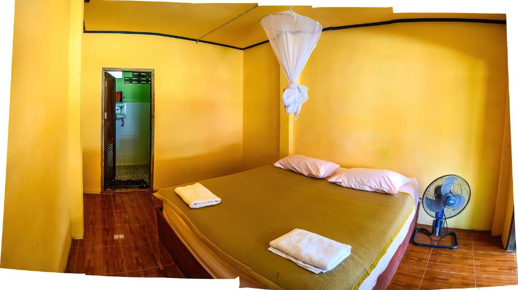 a bedroom with a bed with two towels and a fan at Don Det Sokxay and Mamapieng Budget Guesthouse in Don Det