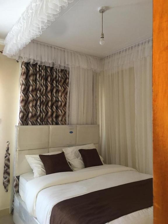 una camera da letto con un grande letto bianco con tende di Mountainview house#122 a Kisumu