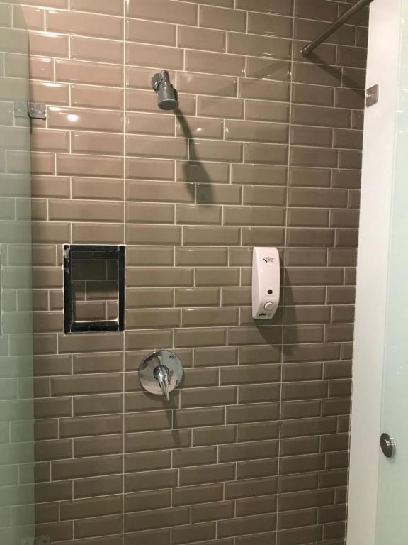 a shower in a bathroom with a brick wall at PassGo Digital Airport Terminal 2 Soekarno Hatta in Rawabagol