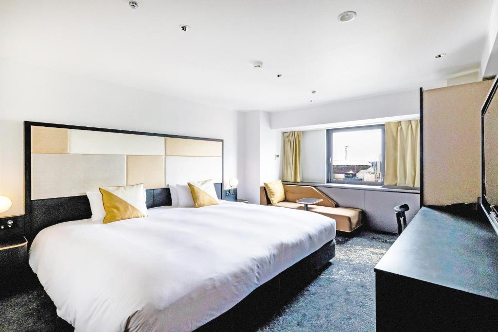 a hotel room with a large bed and a television at Cross Hotel Osaka in Osaka