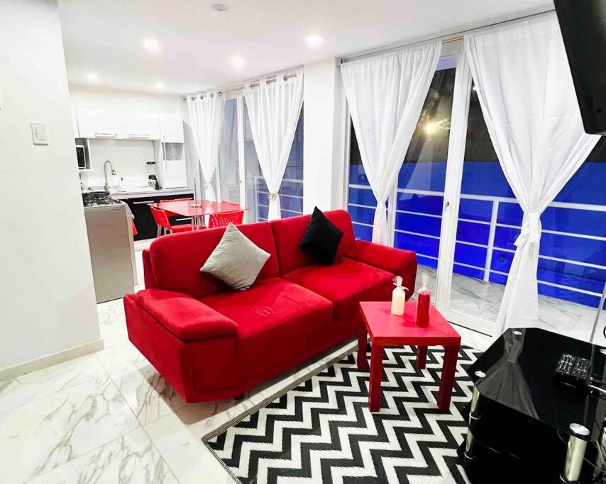 a living room with a red couch and a table at Departamento La Punta E - Piscina - Zona parrilla in Lima