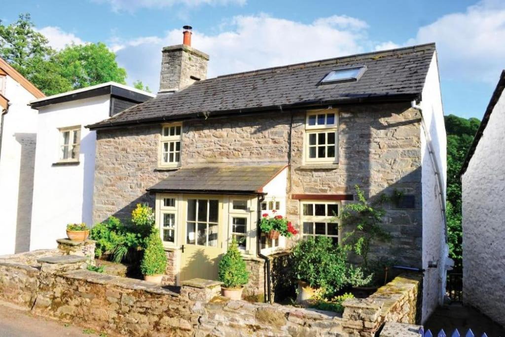an old stone house with a black roof at River Cottage Brecon: Hot Tub, Fire, Balcony, Wifi in Brecon