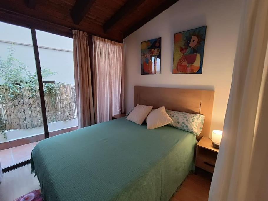 1 dormitorio con cama verde y ventana grande en At Home Realejo, en Granada