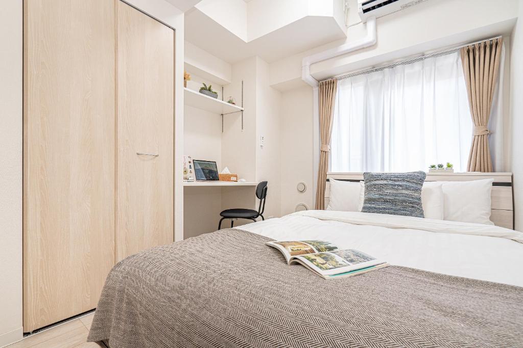 una camera da letto con un letto con un libro sopra di ZAITO Kikukawa SRS Apartment 新築マンション a Tokyo