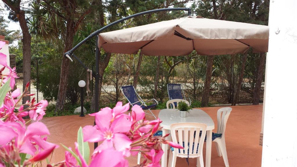 a table and chairs under an umbrella with pink flowers at Casa Vacanze Mari in San Vito lo Capo