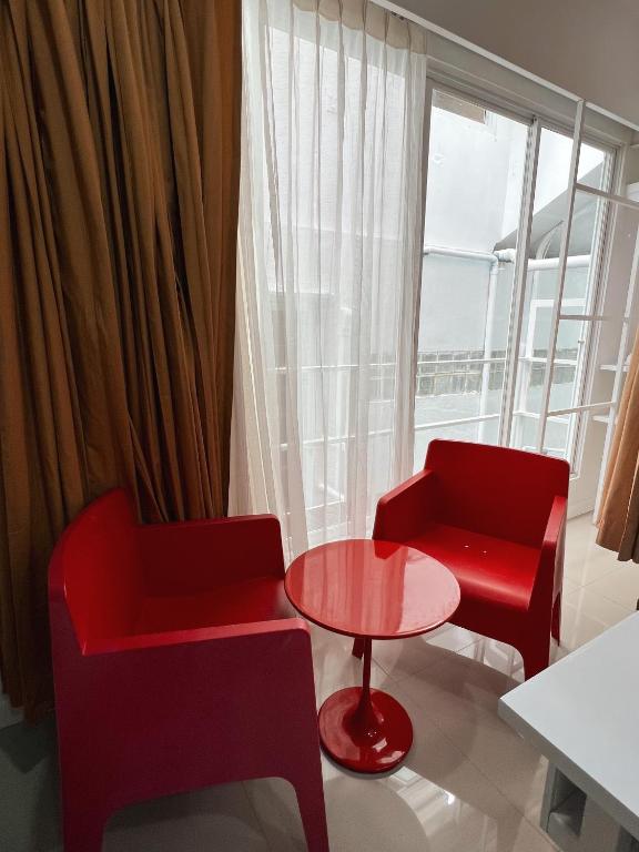 a living room with two red chairs and a table at The Color Kata in Kata Beach