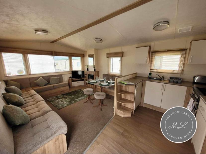 a large living room with a couch and a kitchen at The Meadows 34 - Golden Palm Resort, pet friendly, WiFi & bed linen - Meadow Lakes Caravan & Lodge Hire in Chapel Saint Leonards