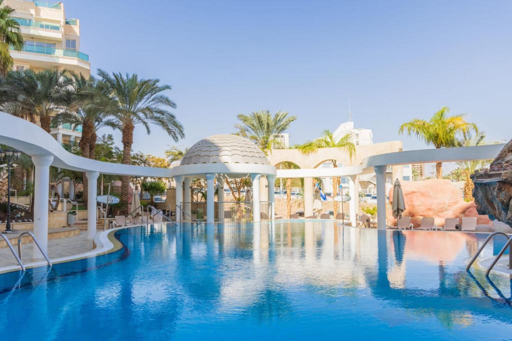 una piscina en un complejo con sillas y árboles en YalaRent Golf Residence 3BR apt in luxury complex with pool, en Eilat