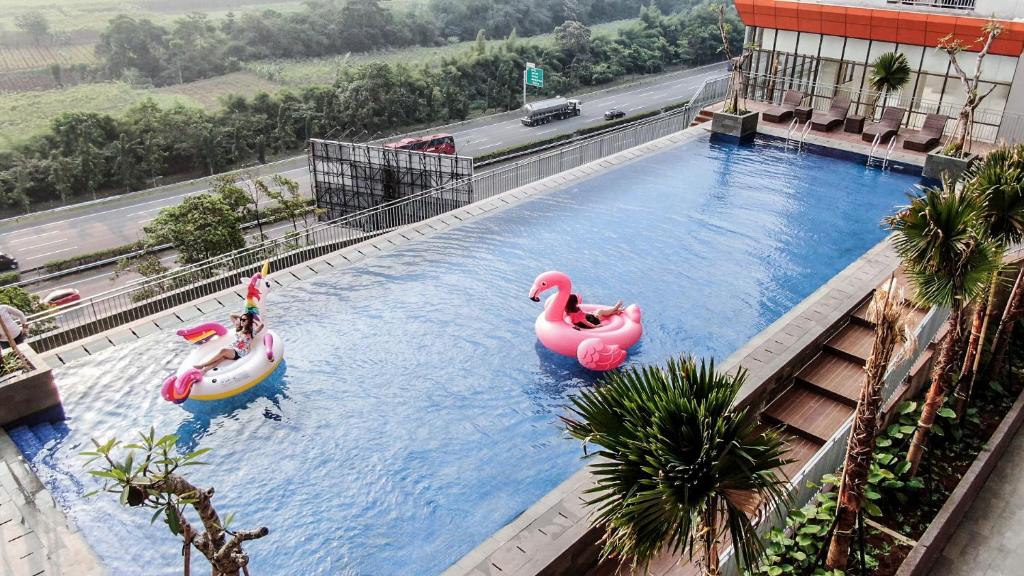 Dos personas están en una piscina en un hotel en Stay G Service Residence Sentul, en Kedungmanggu