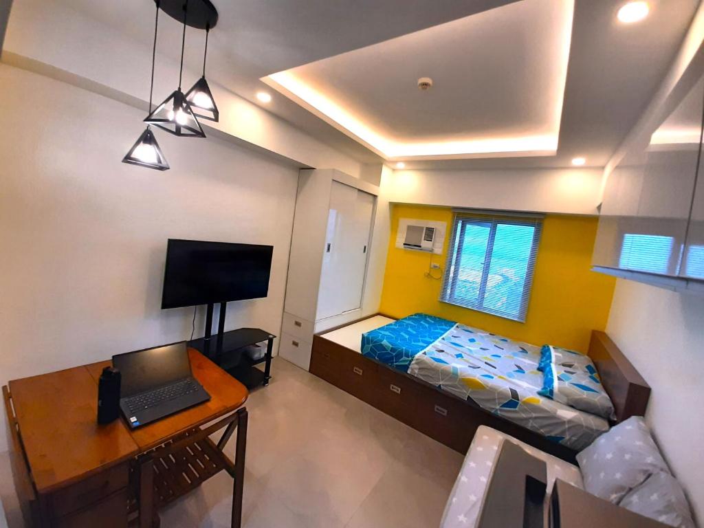 a bedroom with a bed and a desk with a laptop at 1809 Sunvida Tower Condo across SM City Cebu in Cebu City