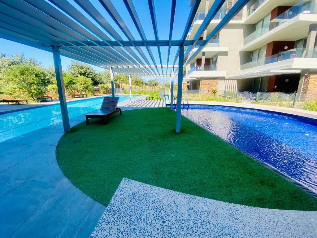 una piscina con un banco junto a un edificio en Dolce vita luxurious apartment, en Umhlanga