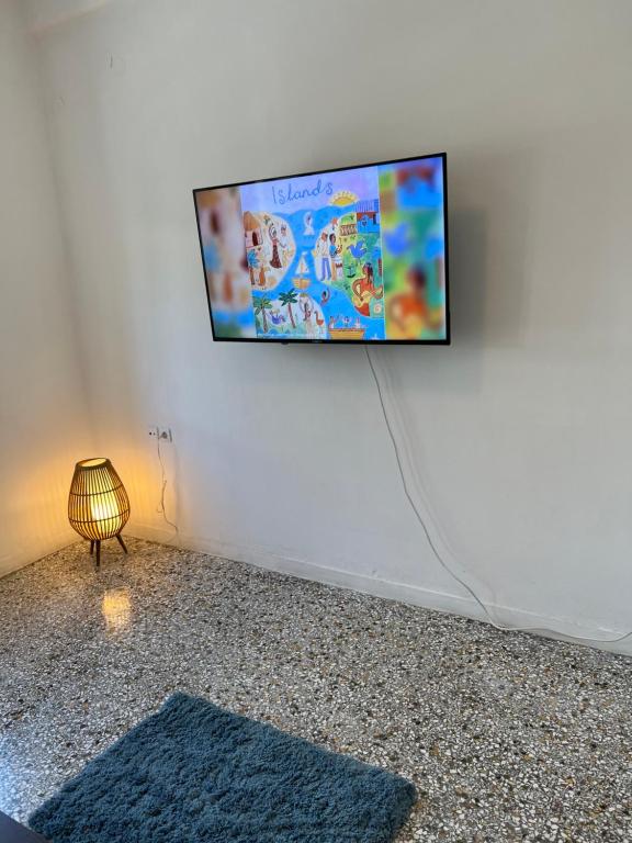 TV de pantalla plana colgada en una pared blanca en Sunchaser Apartments en Igoumenitsa