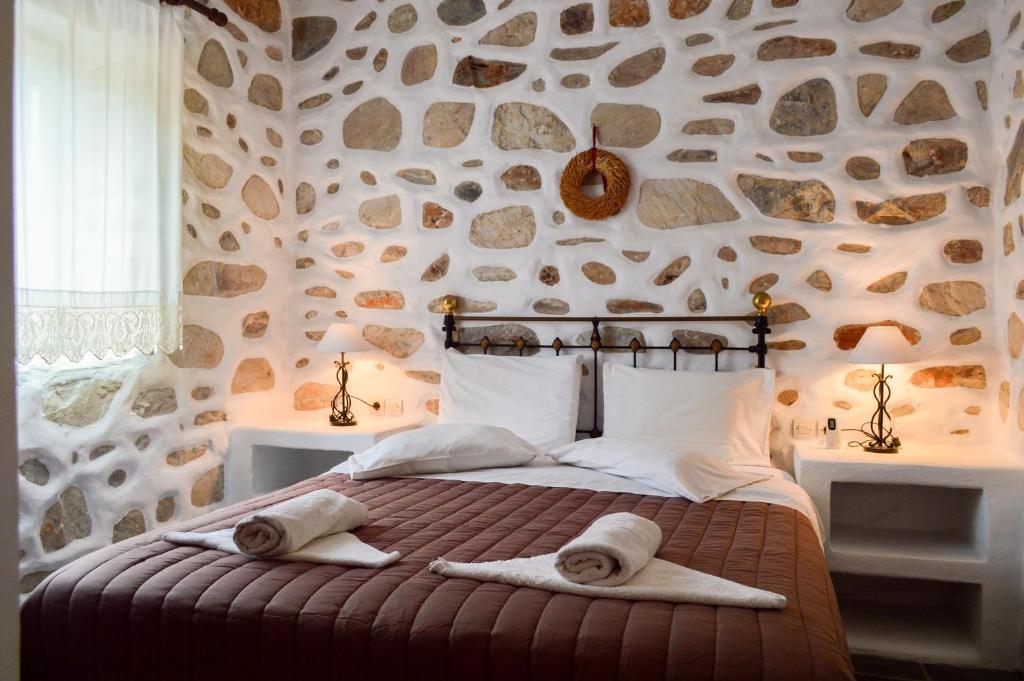 a bedroom with a stone wall with a bed with towels on it at Villa Peristeri in Agios Georgios