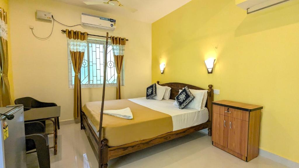 a bedroom with a bed and a desk in it at Santana Guest House in Agonda