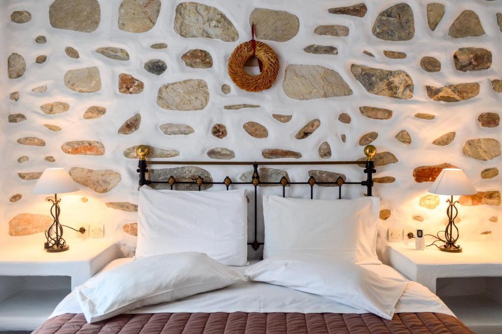 a bedroom with a stone wall with a bed and two lamps at Villa Peristeri in Agios Georgios