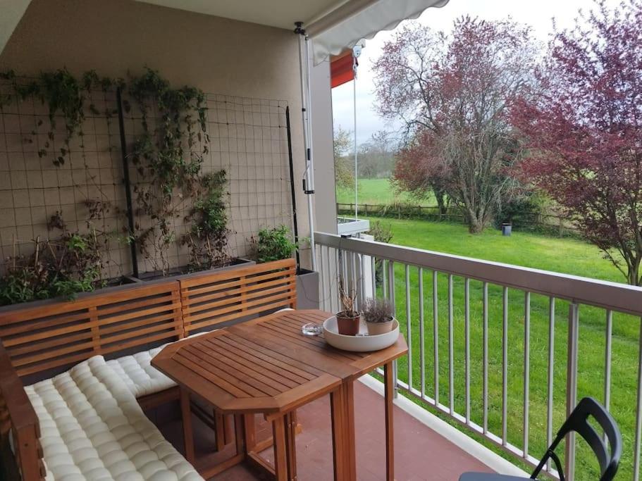 een houten tafel en bank op een balkon met uitzicht bij Near GVA: cosy & luminous cocoon in Ferney-Voltaire