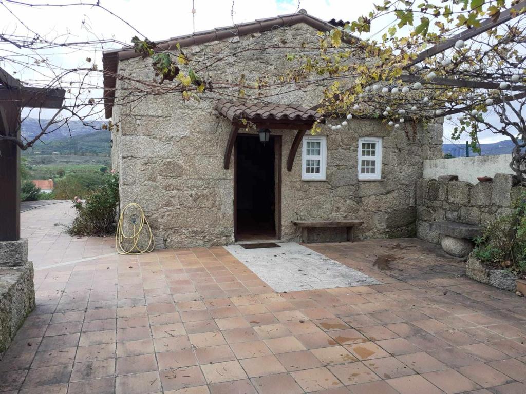 una piccola casa in pietra con una panchina di fronte di Casas do Minério a Guarda
