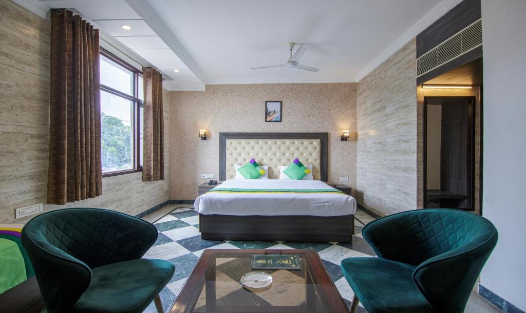 Habitación de hotel con 1 cama y 2 sillas en Treebo Trend Trinetar International, en Jammu